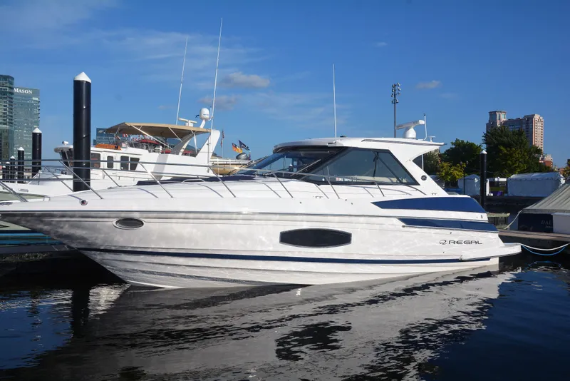 Slide: The Image of 2018 Regal 46 Sport Coupe yacht docked in a marina under clear blue skies. - 2