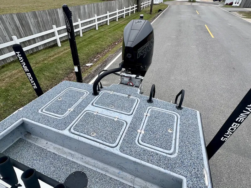 Slide: The Image of 2021 Haynie 25 Magnum boat with motor, parked on a road near a white fence. - 7