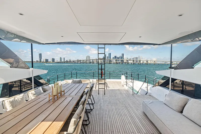 Slide: The Image of Luxurious 2022 Custom Line 106 yacht deck with city skyline view, featuring elegant seating and dining area. - 36