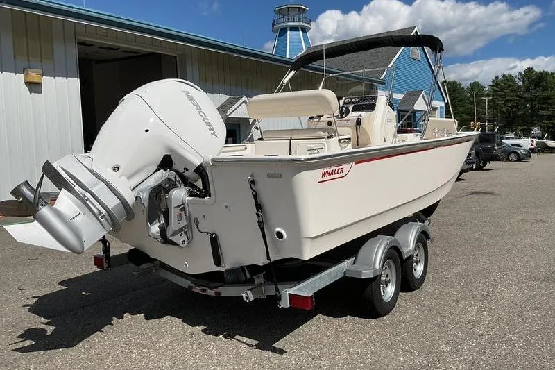 Slide: The Image of 2025 Boston Whaler 210 Montauk boat on trailer, parked outdoors under blue sky. - 11