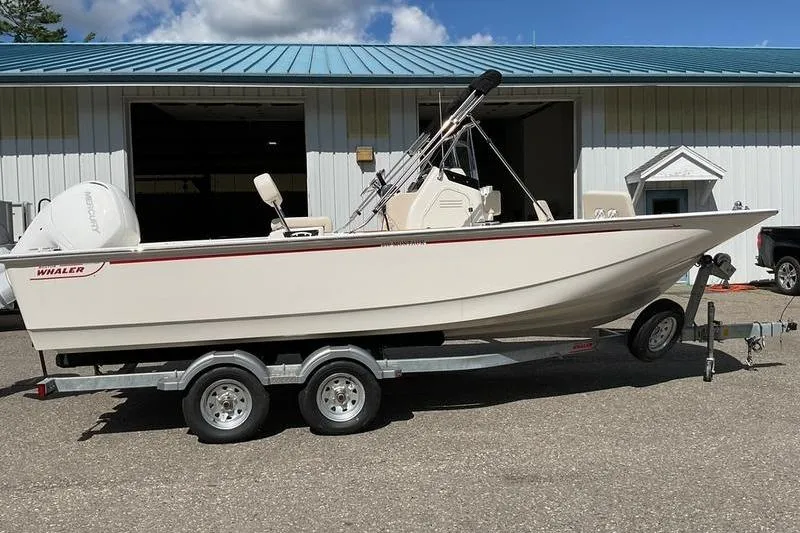 Slide: The Image of 2025 Boston Whaler 210 Montauk boat on trailer, parked outside a building. - 13