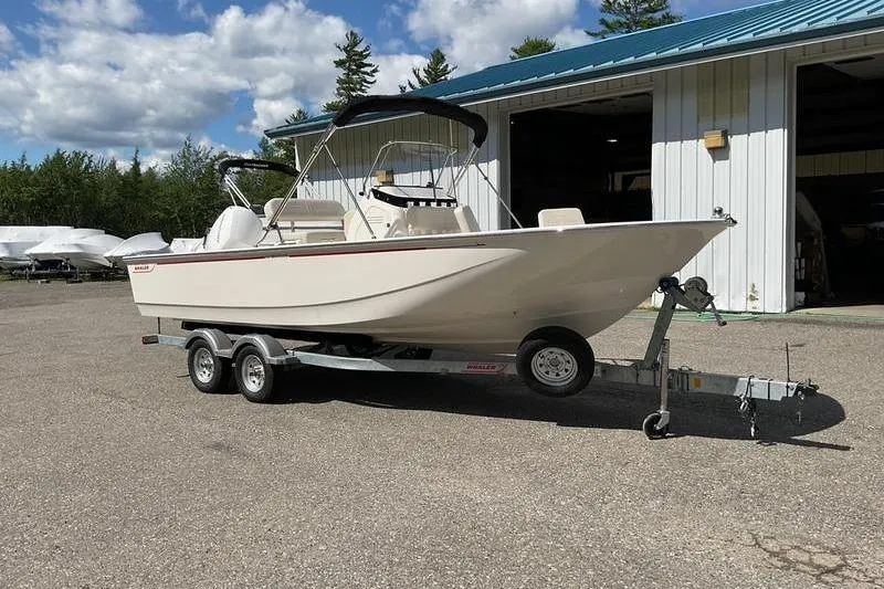 Slide: The Image of 2025 Boston Whaler 210 Montauk boat on trailer, parked outside a warehouse. - 6