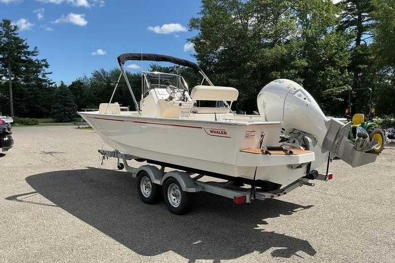 Slide: The Image of 2025 Boston Whaler 210 Montauk boat on trailer, parked outdoors under clear sky. - 7