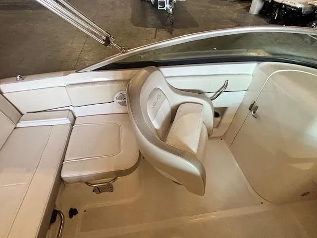 Slide: The Image of 2013 Sea Ray 220 Sundeck interior with beige seating and steering area. - 12