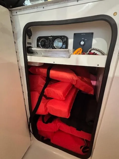 Slide: The Image of Storage compartment in a 2013 Sea Ray 220 Sundeck with life jackets and control panel. - 17
