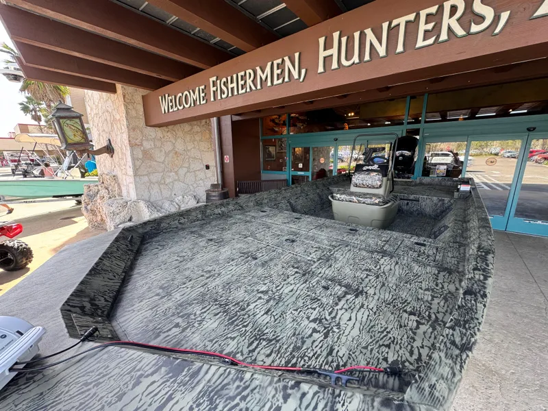 Slide: The Image of 2025 Tracker Grizzly 2072 CC boat displayed outside a store with a welcoming sign. - 2