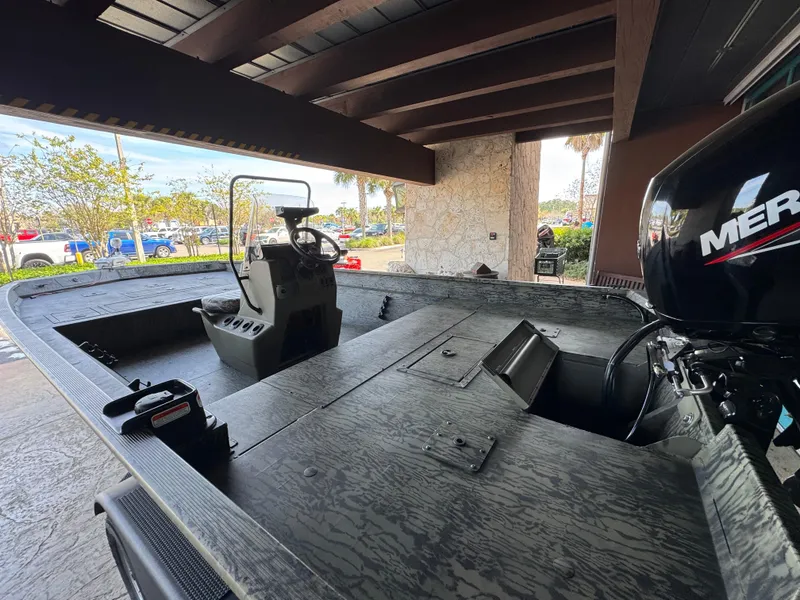 Slide: The Image of 2025 Tracker Grizzly 2072 CC boat with Mercury engine, parked under a wooden canopy. - 3