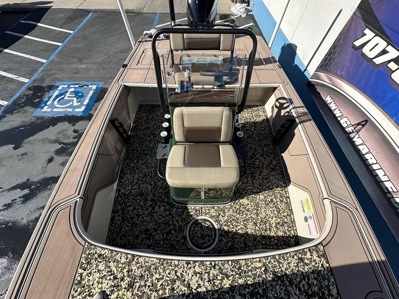 Slide: The Image of 2025 Mako 18 Pro Skiff Backwater Edition boat with camouflage interior, parked in a lot. - 23