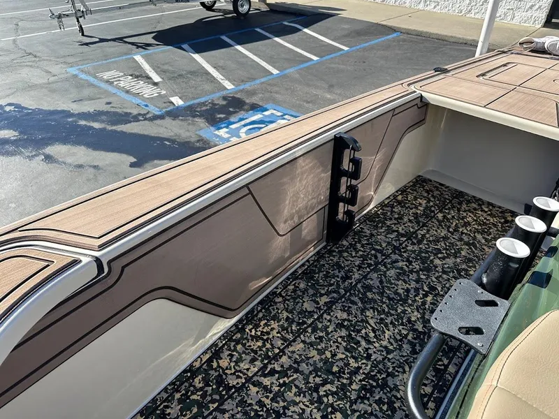 Slide: The Image of 2025 Mako 18 Pro Skiff Backwater Edition interior with camo flooring and rod holders. - 24