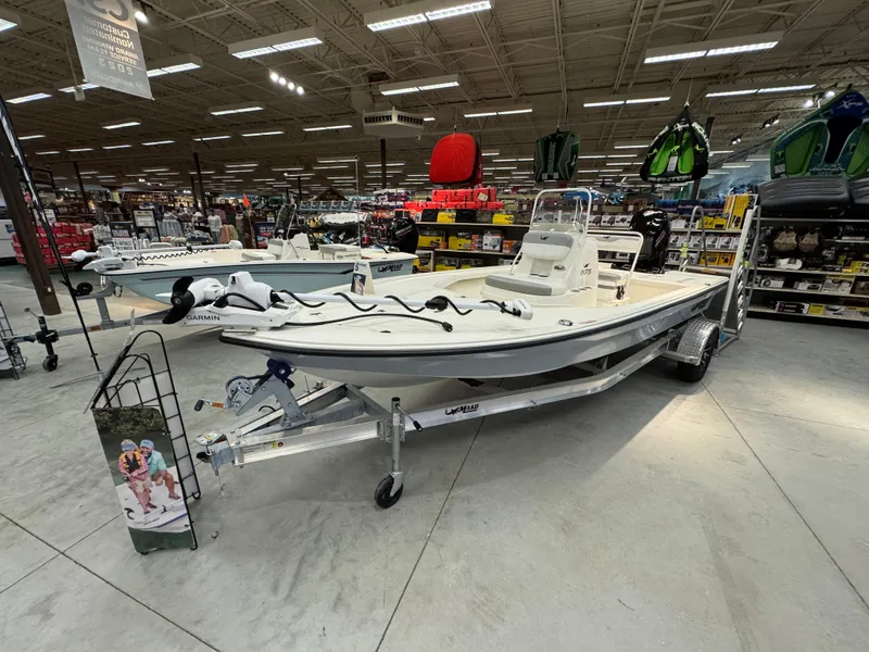 Slide: The Image of 2025 Mako 18 LTS boat displayed in a showroom with fishing gear. - 0