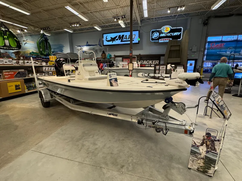 Slide: The Image of 2025 Mako 18 LTS boat displayed in a showroom with fishing gear. - 1