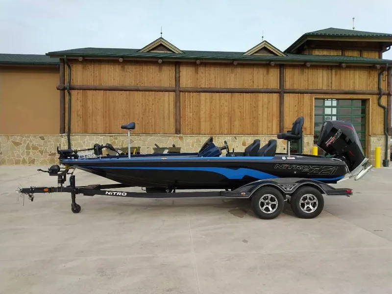 The Image of 2025 Nitro Z21 XL boat on trailer, parked outside a wooden building. - 0