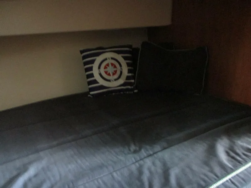 Slide: The Image of 2007 Silverton 33 Convertible cabin with dark bedding and nautical-themed pillow. - 43