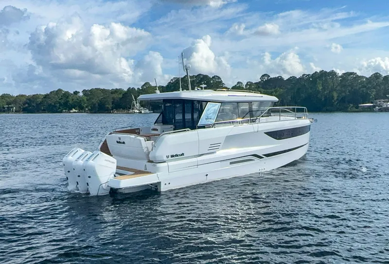 Slide: The Image of 2025 Wellcraft 44 Explorer boat cruising on a serene lake. - 2