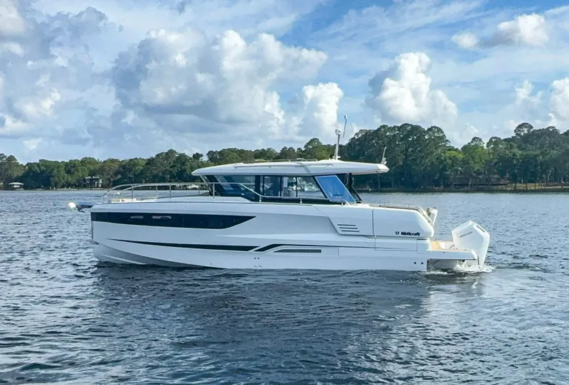 Slide: The Image of 2025 Wellcraft 44 Explorer yacht on a serene lake under a partly cloudy sky. - 4