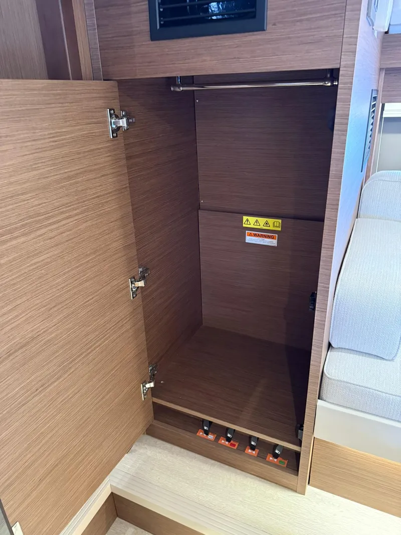 Slide: The Image of 2025 Wellcraft 44 Explorer interior closet with wooden finish and open door. - 45
