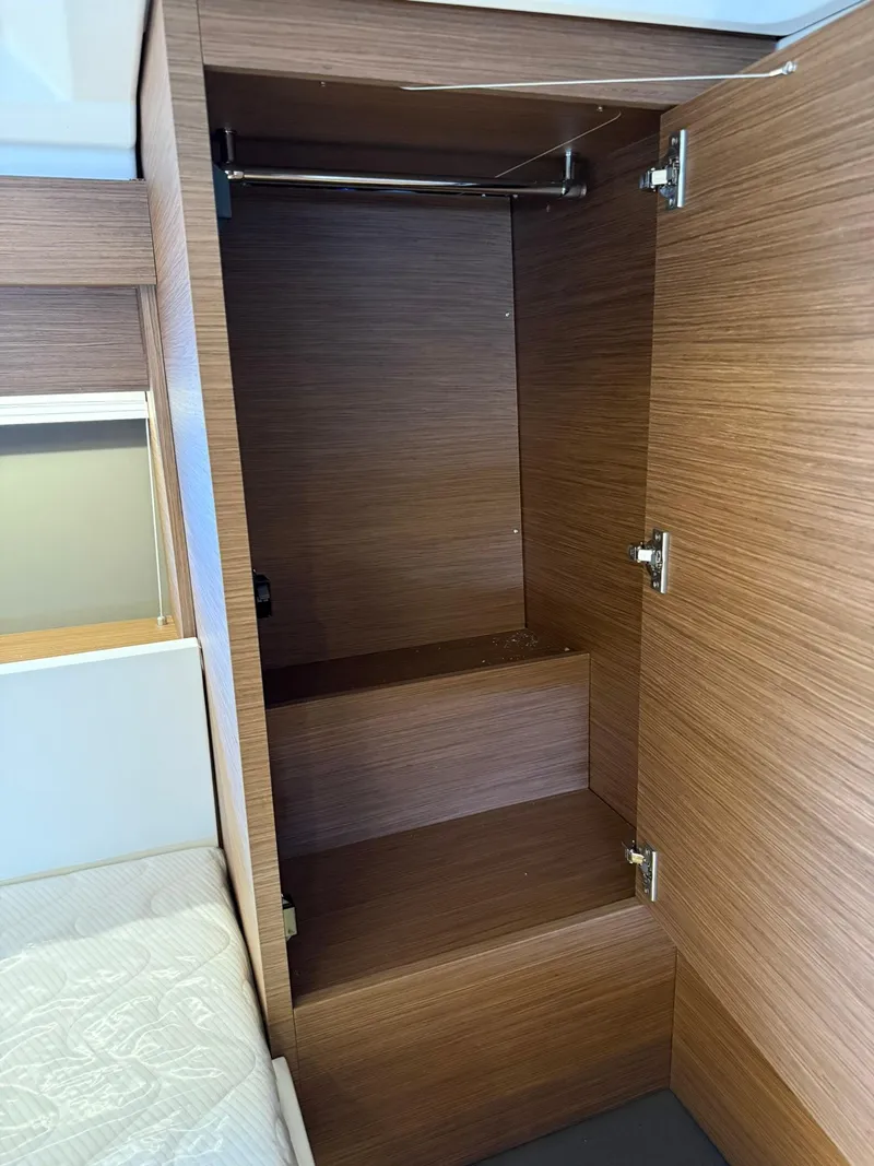 Slide: The Image of 2025 Wellcraft 44 Explorer interior closet with wooden finish and open doors. - 46