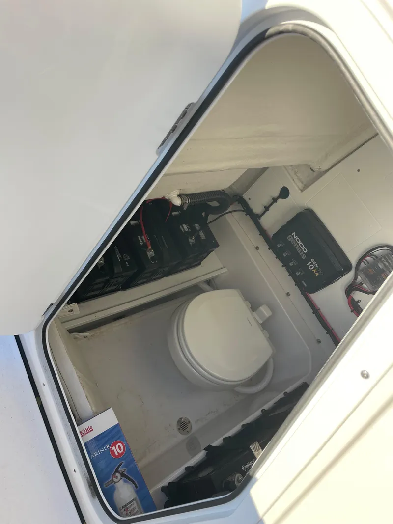 Slide: The Image of 2024 Sportsman Open 232 Center Console boat storage compartment with battery and equipment. - 5