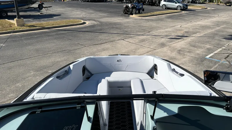 Slide: The Image of 2025 MasterCraft NXT24 boat interior with spacious seating in a parking lot. - 17