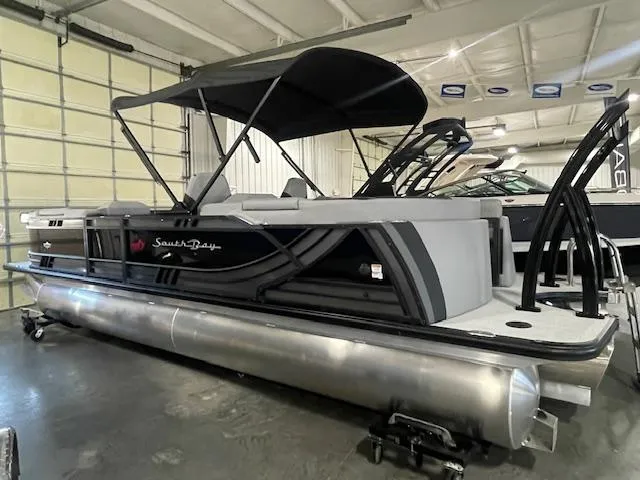 Slide: The Image of 2025 South Bay 500 pontoon boat in showroom, featuring sleek design and canopy. - 0