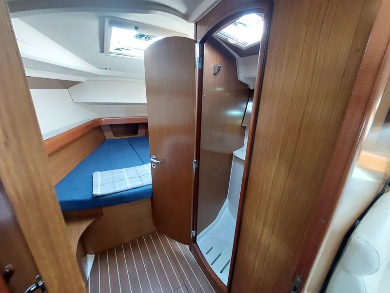 Slide: The Image of Interior cabin of 2006 Jeanneau Sun Odyssey 42 DS sailboat, featuring wood finish and blue bedding. - 35