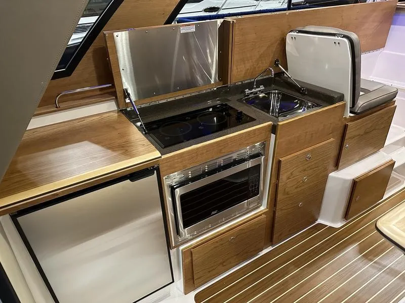 Slide: The Image of 2025 Cutwater C-32 CB LE boat kitchen with modern appliances and wood finish. - 22