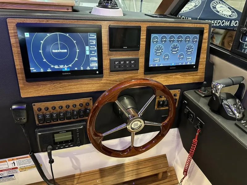 Slide: The Image of 2025 Cutwater C-32 CB LE helm with dual displays, wooden steering wheel, and control panel. - 24