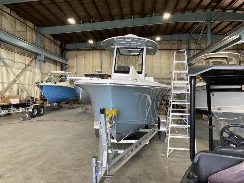 Slide: The Image of 2025 Sea Hunt Ultra 239se boat in a warehouse, on a trailer, with a ladder nearby. - 3