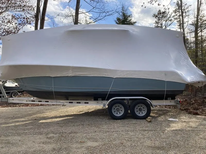 Slide: The Image of 2025 Sea Hunt Ultra 239se boat covered on trailer in wooded area. - 4