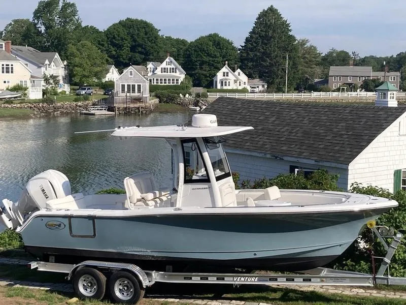 Slide: The Image of 2025 Sea Hunt Ultra 239se boat on trailer by waterfront homes. - 5