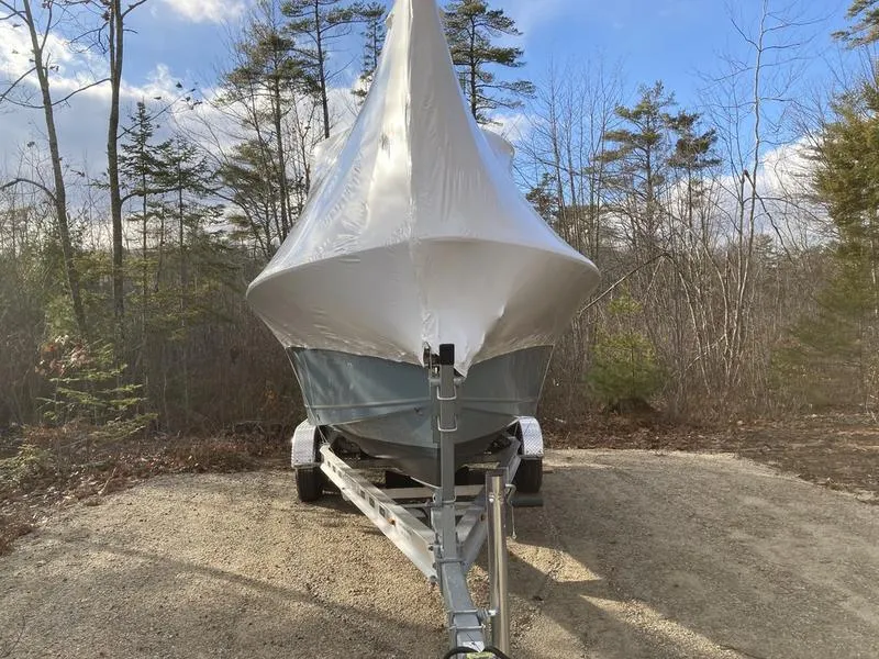 Slide: The Image of 2025 Sea Hunt Ultra 239se boat covered on trailer in wooded area. - 7