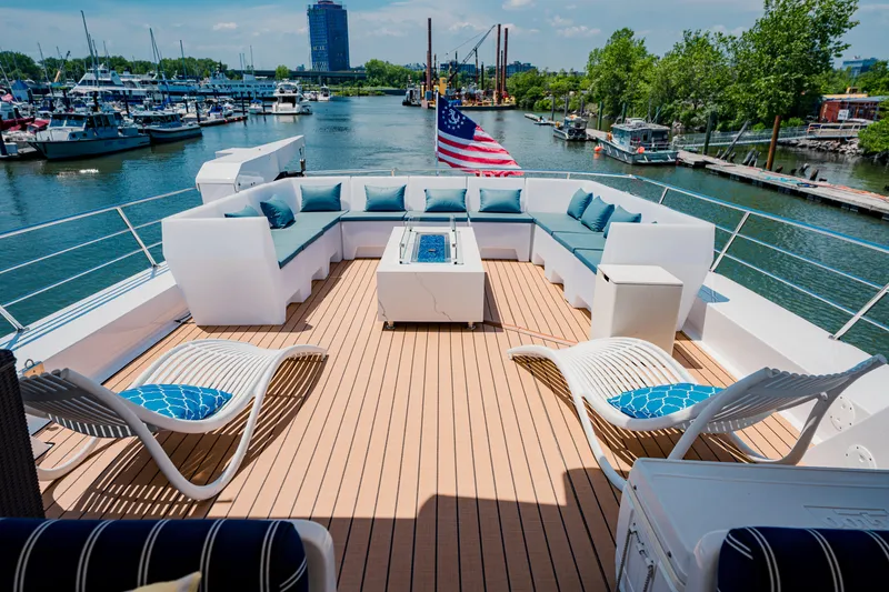 Slide: The Image of Luxurious 1987 Guy Couach 97 yacht deck with seating, American flag, and waterfront view. - 14