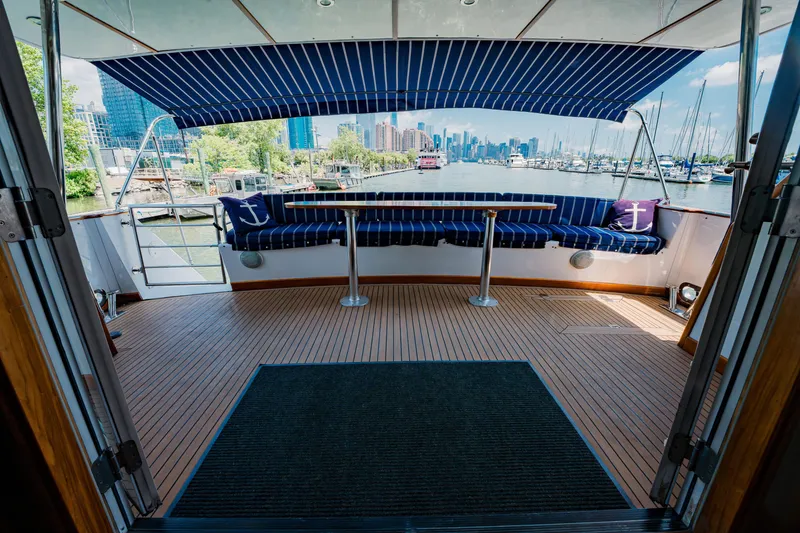 Slide: The Image of Luxurious 1987 Guy Couach 97 yacht deck with striped seating and city skyline view. - 22