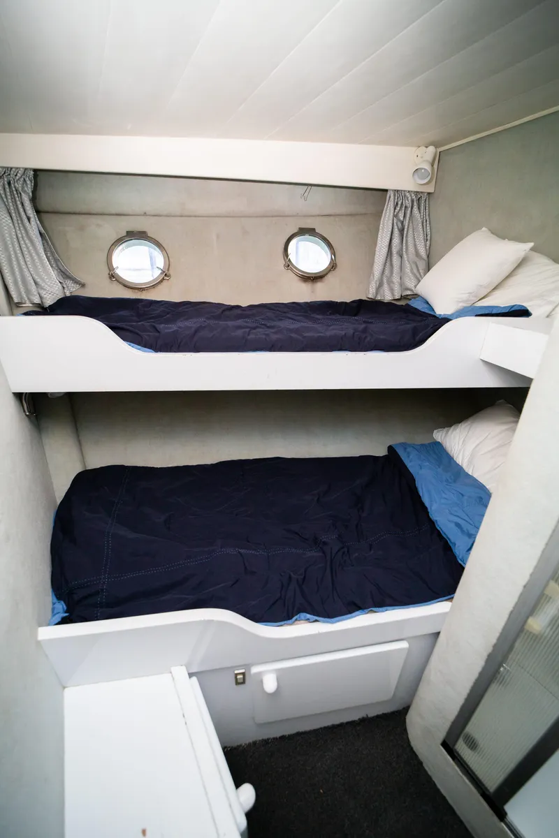 Slide: The Image of Bunk beds in 1987 Guy Couach 97 yacht cabin with portholes and blue bedding. - 43