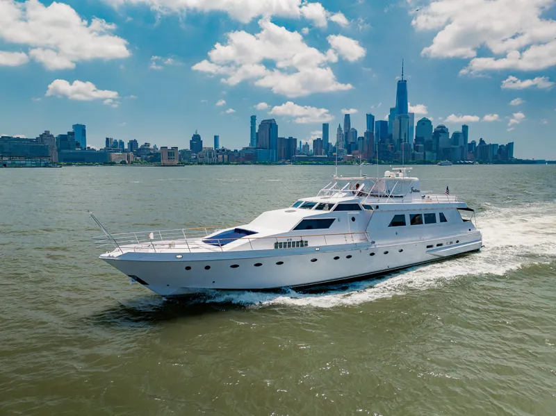 Slide: The Image of Luxurious 1987 Guy Couach 97 yacht cruising near a city skyline under a blue sky. - 9
