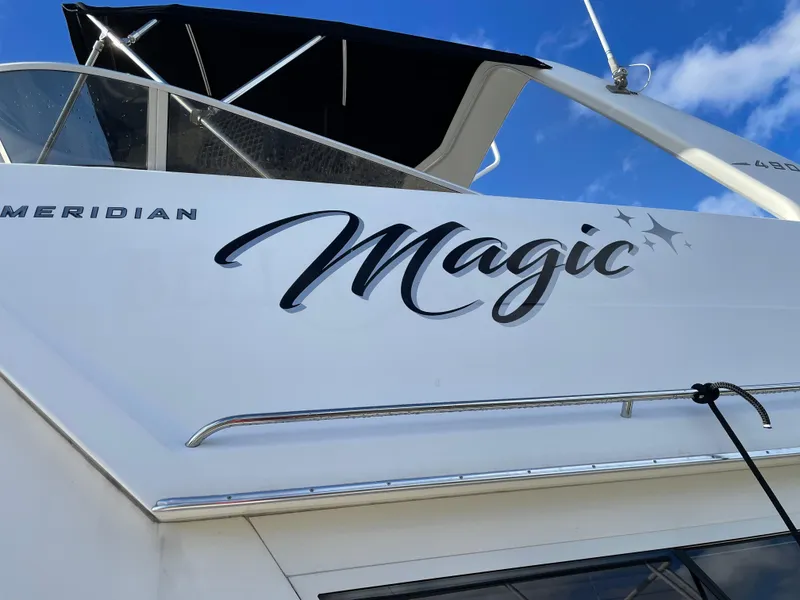 Slide: The Image of 2004 Meridian 490 Pilothouse yacht with "Magic" name, sleek design, and blue sky background. - 9