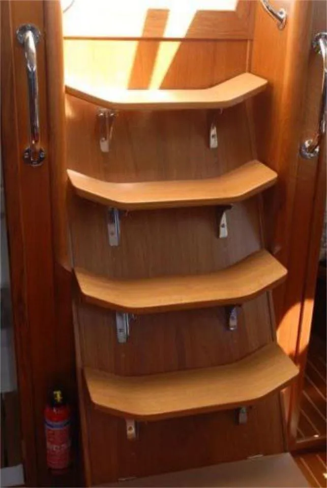 Slide: The Image of Wooden interior stairs on a 2025 Rustler 42 yacht, featuring sleek handrails and a fire extinguisher. - 18