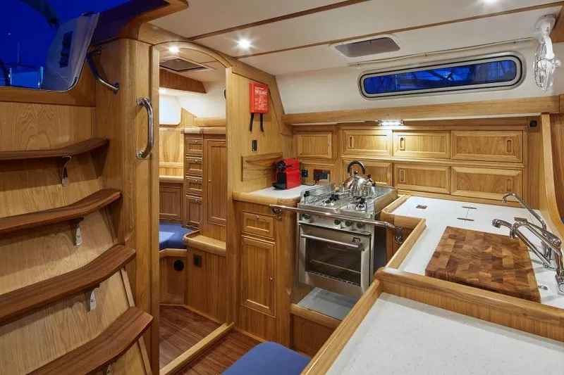 Slide: The Image of Luxurious 2025 Rustler 42 yacht interior with wooden cabinetry and modern kitchen amenities. - 19