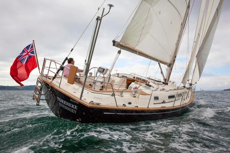 Slide: The Image of Sailing yacht Rustler 42, 2025 model, navigating ocean waters with a red ensign flag. - 5