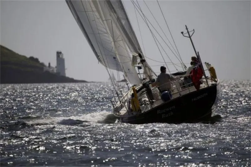 Slide: The Image of Sailing yacht Rustler 42, 2025 model, gliding on shimmering water near a lighthouse. - 8