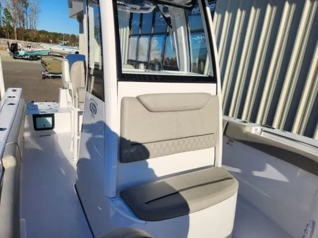 Slide: The Image of 2025 Sportsman Heritage 231 boat with cushioned seating and outboard motor in a marina. - 14