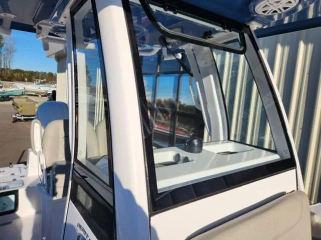 Slide: The Image of 2025 Sportsman Heritage 231 boat with outboard motor, docked near a building. - 15