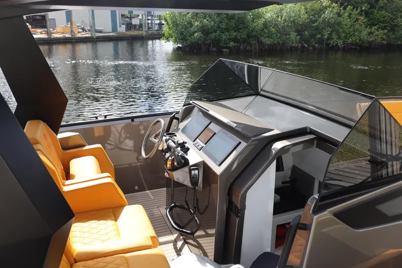 Slide: The Image of 2021 Vanquish Yachts VQ40 interior with orange seating and modern dashboard on a calm river. - 16