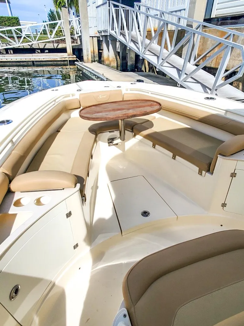 Slide: The Image of 2017 Scout 275 LXF boat interior with beige seating and wooden table. - 3