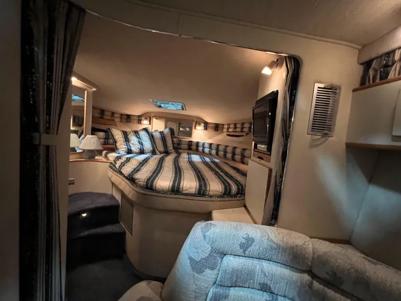 Slide: The Image of Cozy interior of 1992 Sea Ray 370 Express Cruiser with striped bedding and TV. - 19