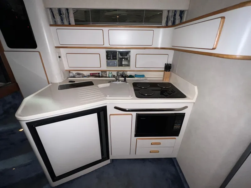 Slide: The Image of Compact kitchen in a 1992 Sea Ray 370 Express Cruiser with stove, sink, and microwave. - 24