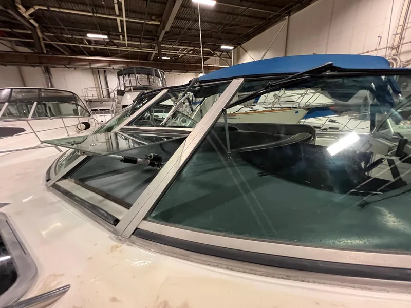 Slide: The Image of 1992 Sea Ray 370 Express Cruiser in indoor storage, showcasing windshield and blue canopy. - 9