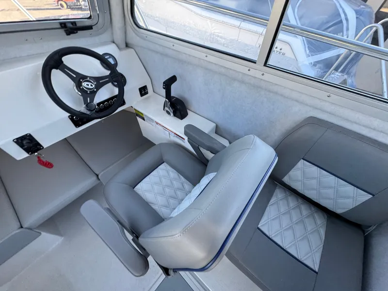 Slide: The Image of 2025 Defiance Admiral 220 EX boat interior with steering wheel and cushioned seating. - 6