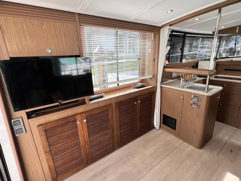 Slide: The Image of 2019 Beneteau Swift Trawler 44 interior with TV, wooden cabinetry, and modern kitchen. - 11