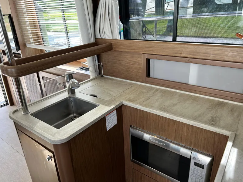 Slide: The Image of 2019 Beneteau Swift Trawler 44 kitchen with sink, microwave, and wooden cabinetry. - 15